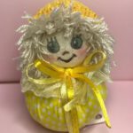 عروسک دست دوز پارچه‌ای دست ساز زرد با موهای سفید پفی و روبان زرد