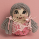 عروسک دست دوز پوفینو صورتی گل‌دار، تور سفید، روبان صورتی و موهای کاموایی خاکستری، مناسب برای دکور اتاق کودک و هدیه خاص